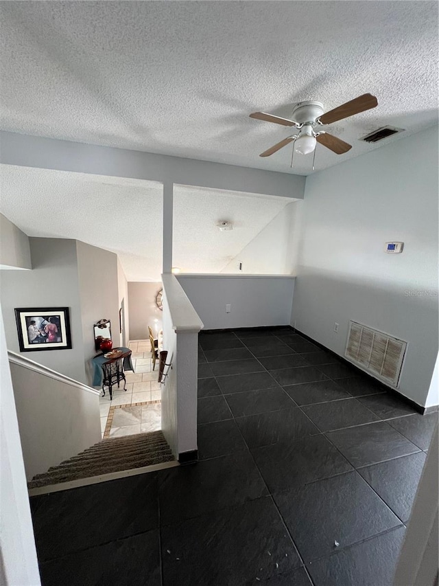 tiled spare room featuring ceiling fan and a textured ceiling