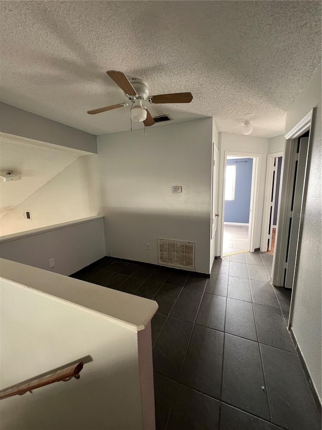 hall featuring dark tile patterned flooring and a textured ceiling