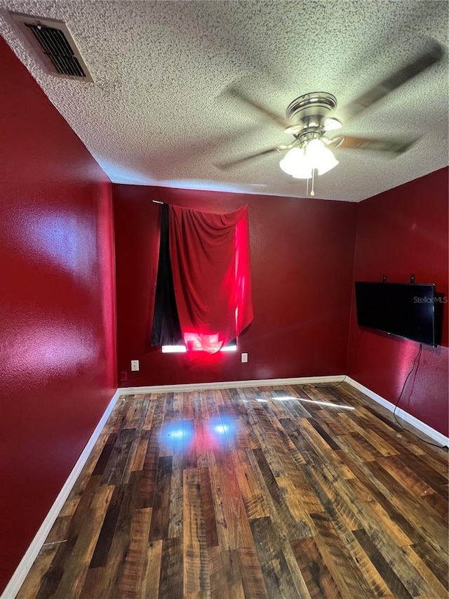 unfurnished room featuring ceiling fan, dark wood-type flooring, and a textured ceiling