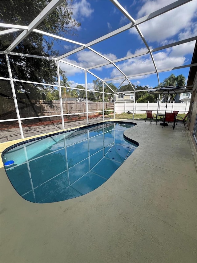 view of swimming pool featuring glass enclosure and a patio area