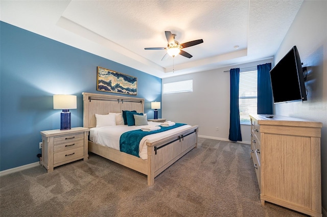 bedroom featuring a raised ceiling, ceiling fan, a textured ceiling, and dark carpet