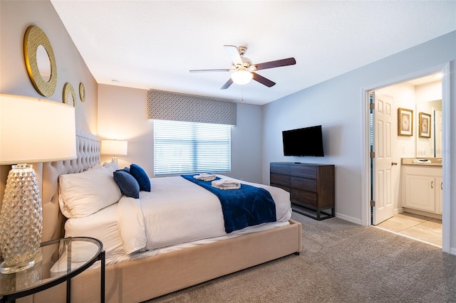 bedroom featuring ceiling fan, light colored carpet, and ensuite bathroom