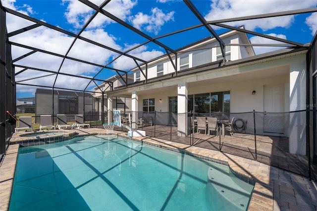 view of pool with a patio area, glass enclosure, and an in ground hot tub