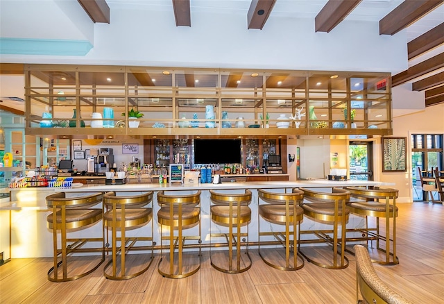 bar featuring beamed ceiling and light hardwood / wood-style flooring