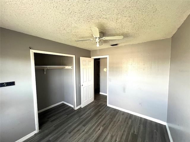 unfurnished bedroom with ceiling fan, dark hardwood / wood-style flooring, a textured ceiling, and a closet