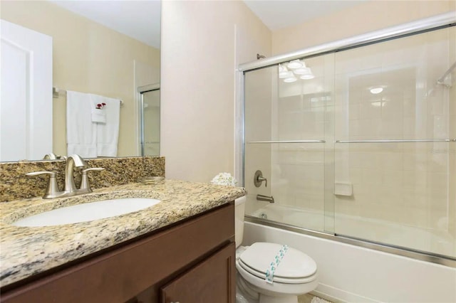 full bathroom featuring vanity, toilet, and bath / shower combo with glass door