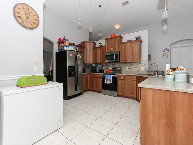 kitchen with backsplash, sink, appliances with stainless steel finishes, decorative light fixtures, and kitchen peninsula