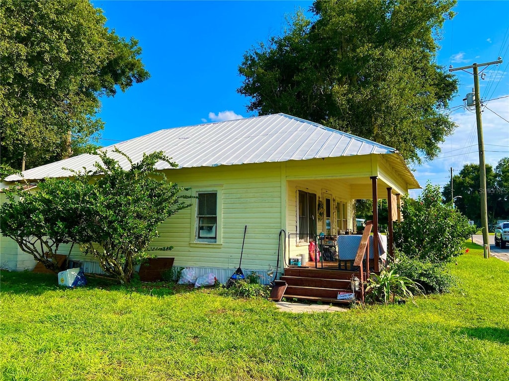 back of property with a lawn and covered porch