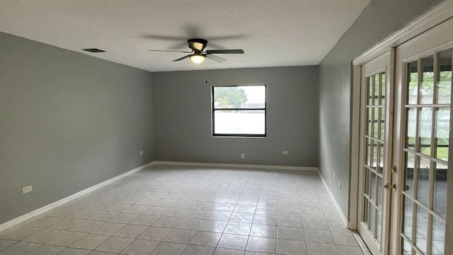 empty room with ceiling fan, light tile patterned floors, a textured ceiling, and french doors