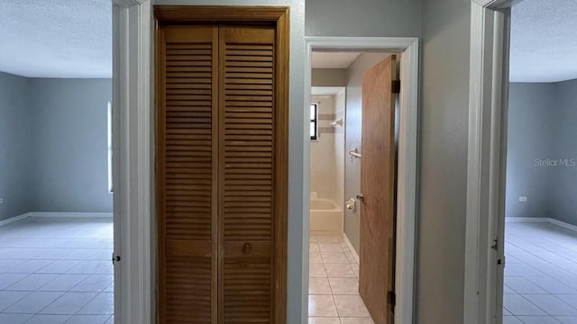 hallway featuring light tile patterned floors and a textured ceiling