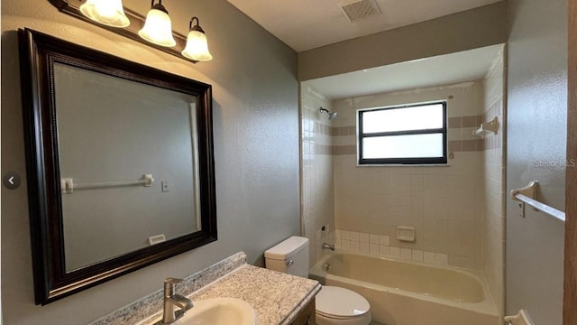 full bathroom with vanity, tiled shower / bath combo, and toilet