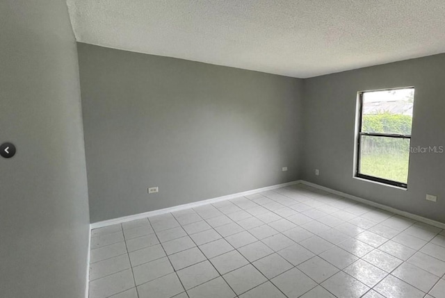 tiled empty room with a textured ceiling