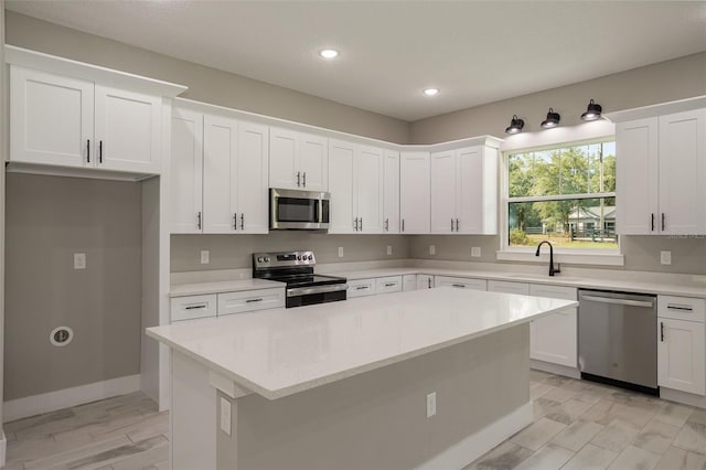 kitchen featuring white cabinets, stainless steel appliances, a kitchen island, and sink