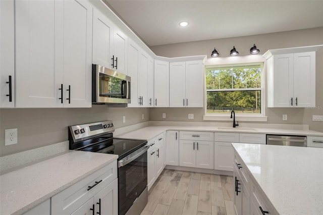 kitchen with white cabinetry, sink, stainless steel appliances, and light stone counters