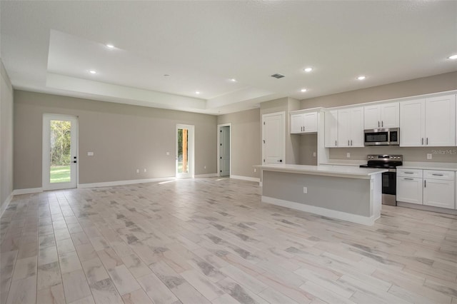 kitchen featuring appliances with stainless steel finishes, light wood-type flooring, white cabinetry, and a kitchen island