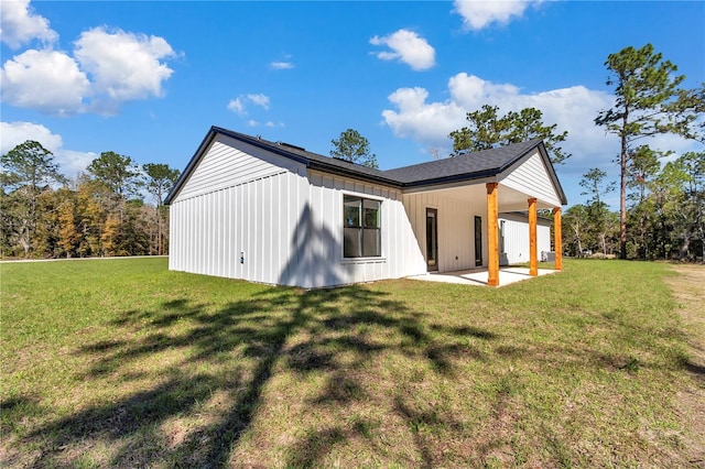 back of house featuring board and batten siding, a patio area, and a lawn