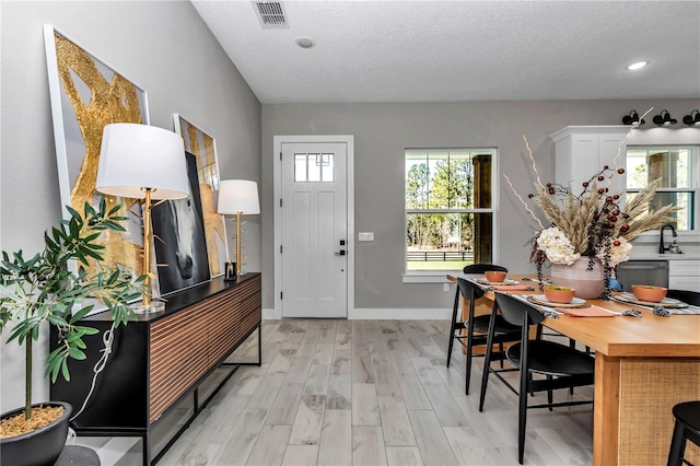 foyer entrance featuring recessed lighting, visible vents, light wood-style flooring, a textured ceiling, and baseboards