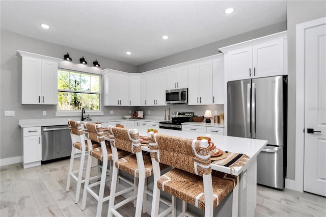 kitchen featuring light countertops, appliances with stainless steel finishes, and a kitchen breakfast bar