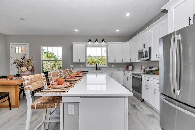 kitchen with stainless steel appliances, a breakfast bar, light countertops, and plenty of natural light