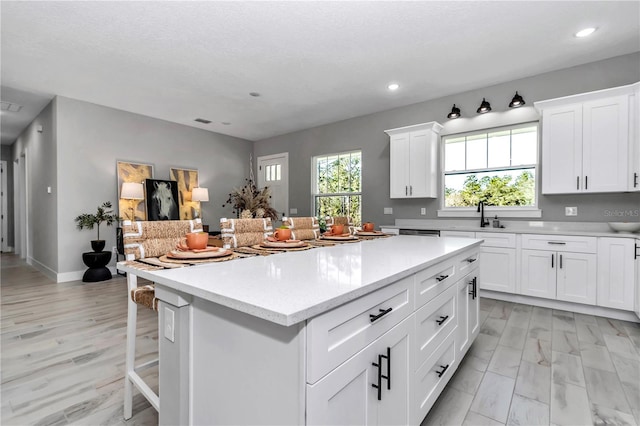 kitchen with a kitchen island, recessed lighting, white cabinetry, and a sink