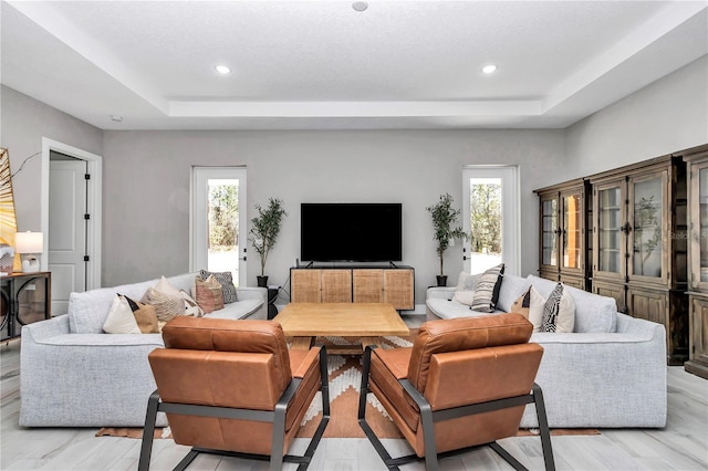 living room with plenty of natural light, a raised ceiling, and recessed lighting