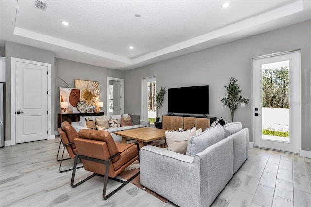 living area with plenty of natural light, a tray ceiling, and recessed lighting