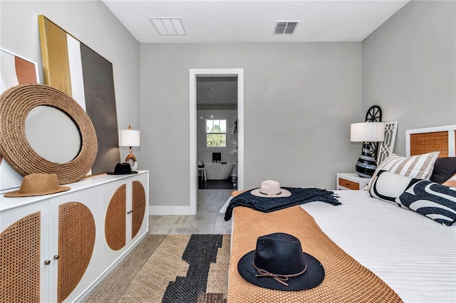 bedroom featuring visible vents, a textured ceiling, baseboards, and wood finished floors