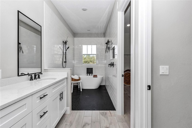 full bath with wood tiled floor, a freestanding bath, and vanity