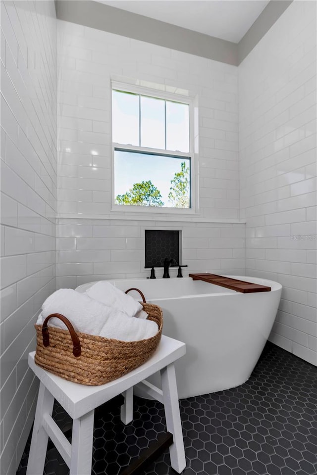 bathroom featuring tile patterned flooring, a freestanding tub, and tile walls