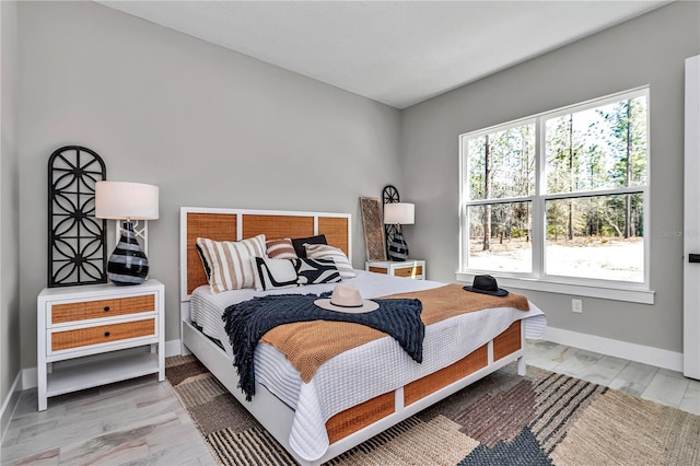 bedroom with light wood-type flooring, multiple windows, and baseboards