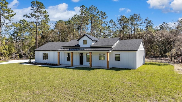 modern farmhouse style home featuring metal roof, a porch, roof with shingles, a front lawn, and a standing seam roof