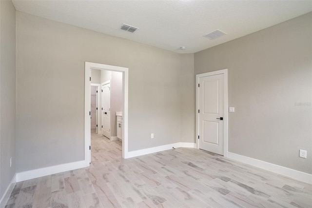 empty room with light hardwood / wood-style floors and a textured ceiling