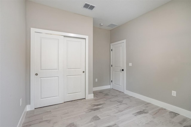 unfurnished bedroom with light wood-type flooring and a closet