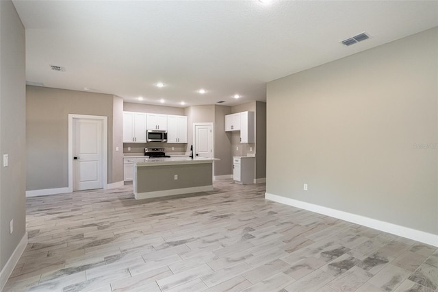 kitchen with white cabinetry, sink, an island with sink, light hardwood / wood-style floors, and appliances with stainless steel finishes