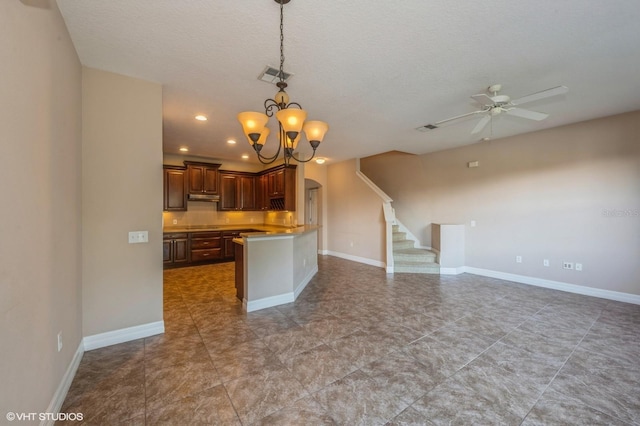 kitchen with kitchen peninsula, a textured ceiling, ceiling fan with notable chandelier, and decorative light fixtures