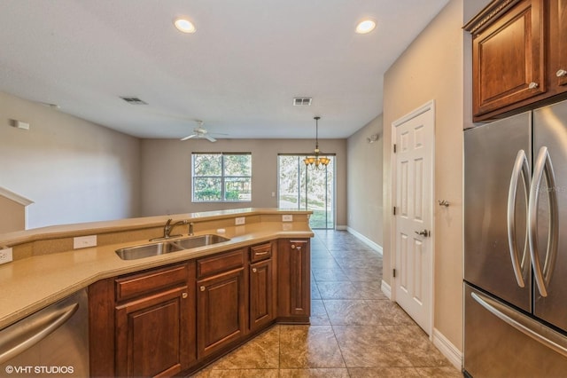 kitchen featuring ceiling fan with notable chandelier, sink, stainless steel appliances, and hanging light fixtures