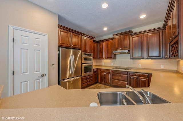 kitchen with stainless steel refrigerator, stovetop, a textured ceiling, and sink