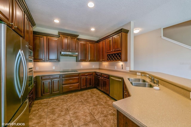 kitchen with sink, light tile patterned floors, a textured ceiling, appliances with stainless steel finishes, and kitchen peninsula