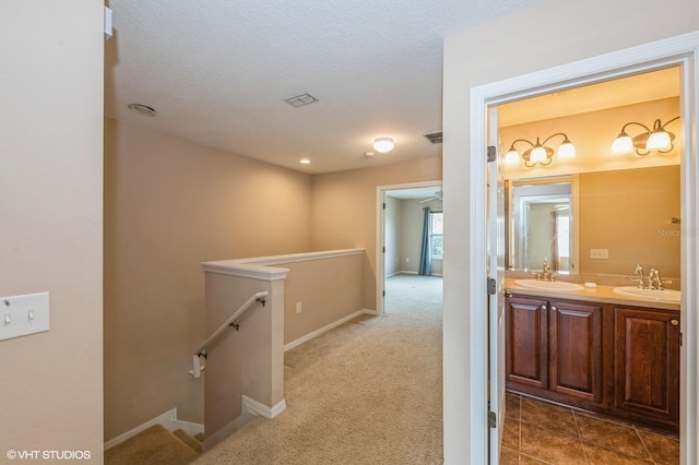 hall featuring carpet flooring, a textured ceiling, and sink