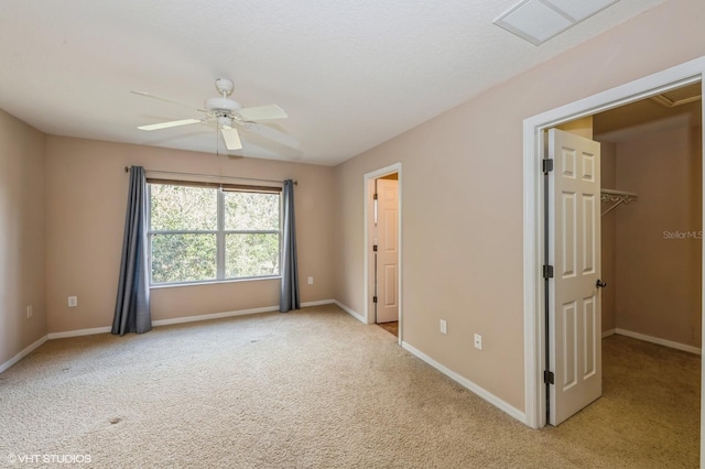 unfurnished bedroom featuring a closet, light colored carpet, a spacious closet, and ceiling fan