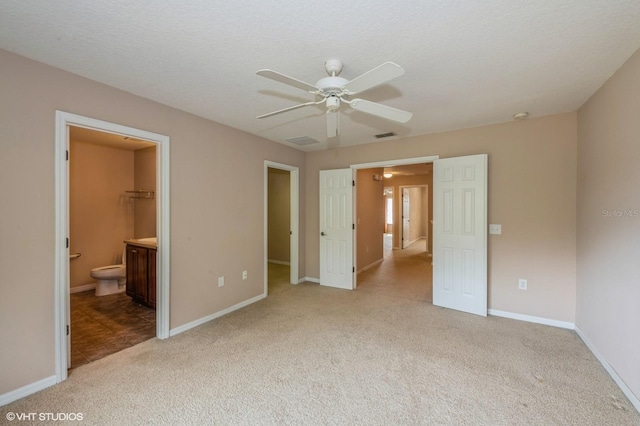 unfurnished bedroom with light carpet, a walk in closet, ceiling fan, a textured ceiling, and connected bathroom