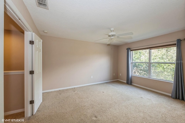 carpeted spare room featuring a textured ceiling and ceiling fan