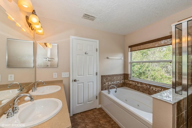 bathroom featuring tile patterned flooring, vanity, a bath, and a textured ceiling