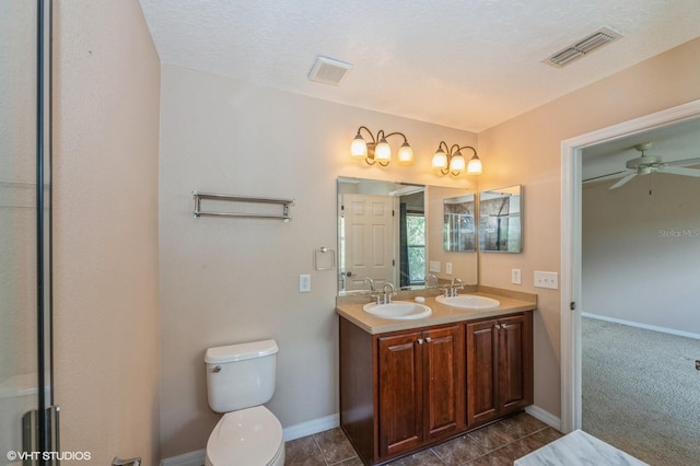 bathroom with ceiling fan, vanity, a textured ceiling, and toilet