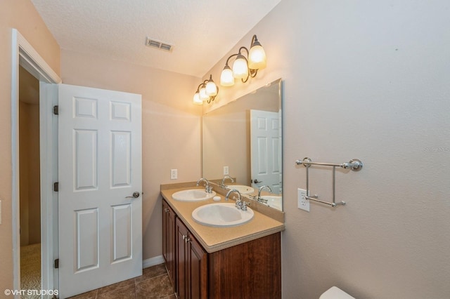 bathroom with tile patterned flooring, vanity, and a textured ceiling