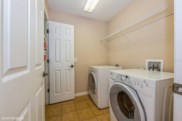 washroom featuring a textured ceiling, separate washer and dryer, and light tile patterned flooring