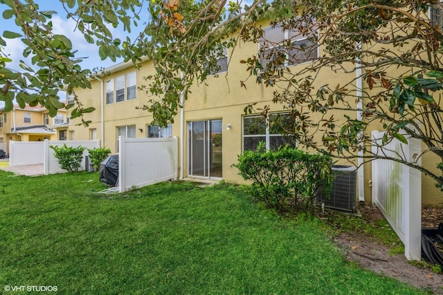 back of property featuring a yard and central AC