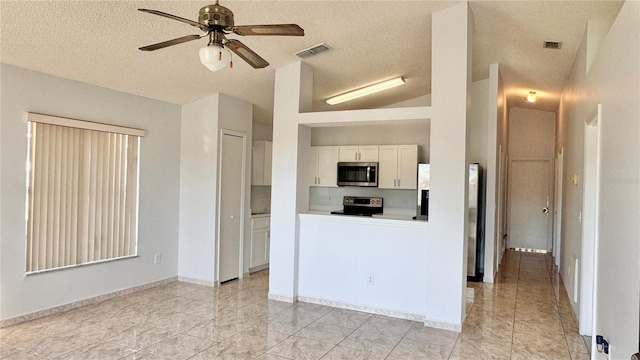 kitchen with white cabinets, vaulted ceiling, ceiling fan, a textured ceiling, and appliances with stainless steel finishes