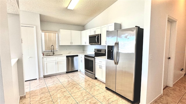 kitchen with white cabinets, stainless steel appliances, lofted ceiling, and sink