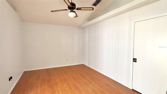 empty room featuring ceiling fan, wood-type flooring, lofted ceiling, and a textured ceiling